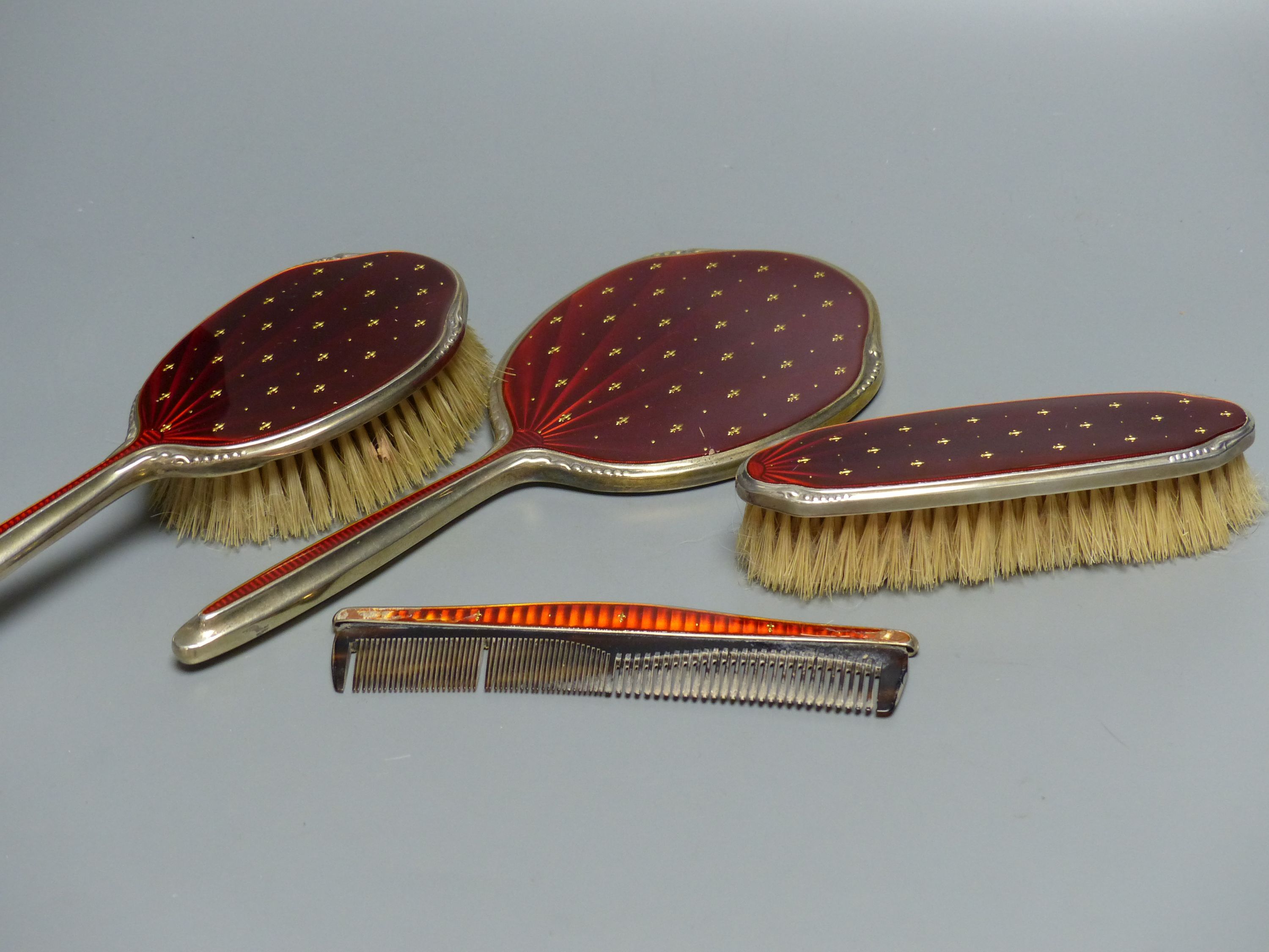 A four-piece silver-gilt and scarlet enamel-mounted dressing table set with fleur de lys decoration, Birmingham 1965